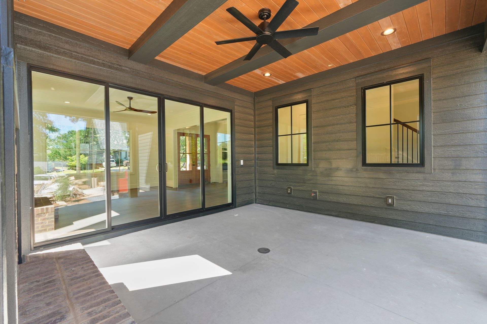 A large patio with sliding glass doors and a ceiling fan.