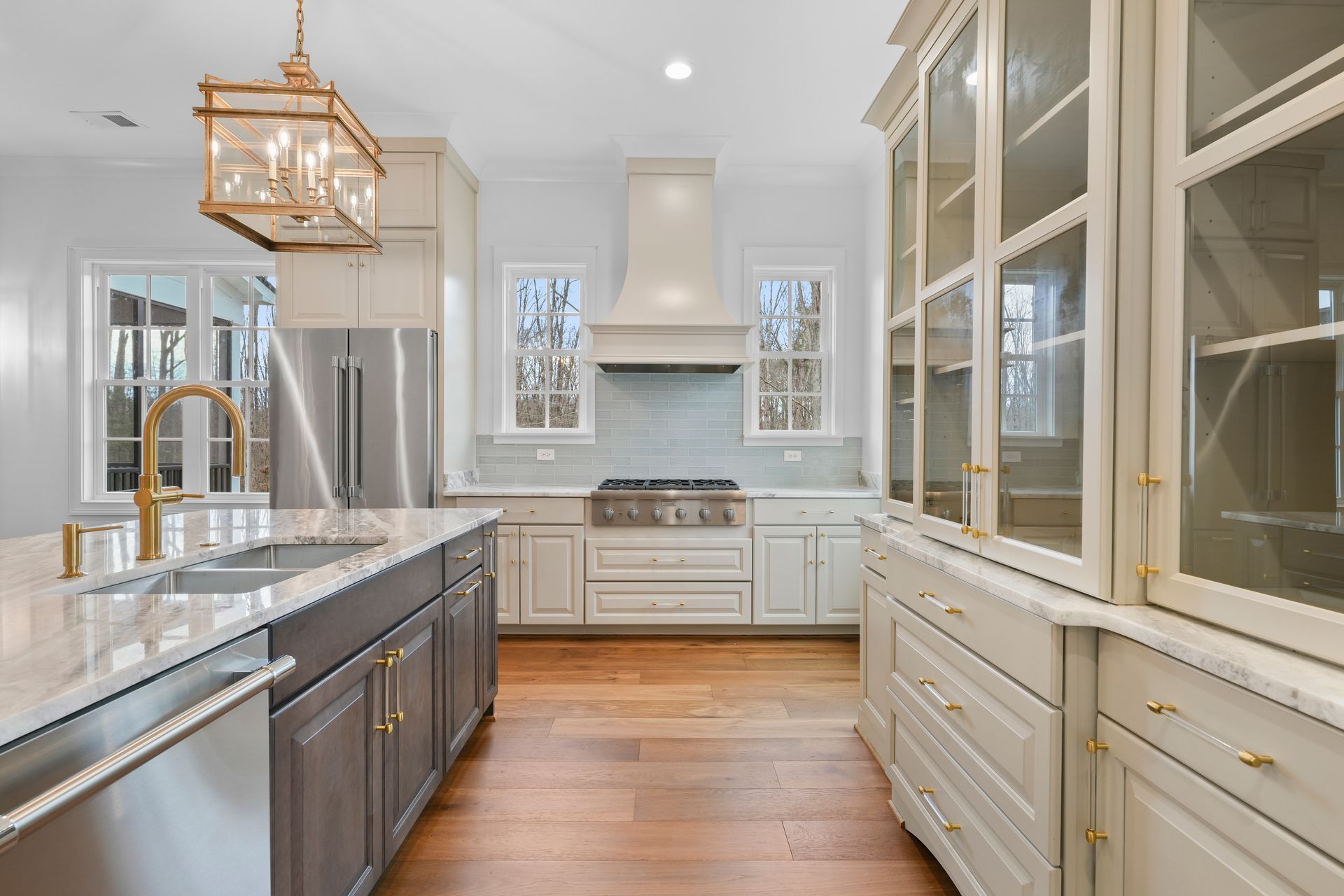 A kitchen with stainless steel appliances , white cabinets , hardwood floors and a large island.