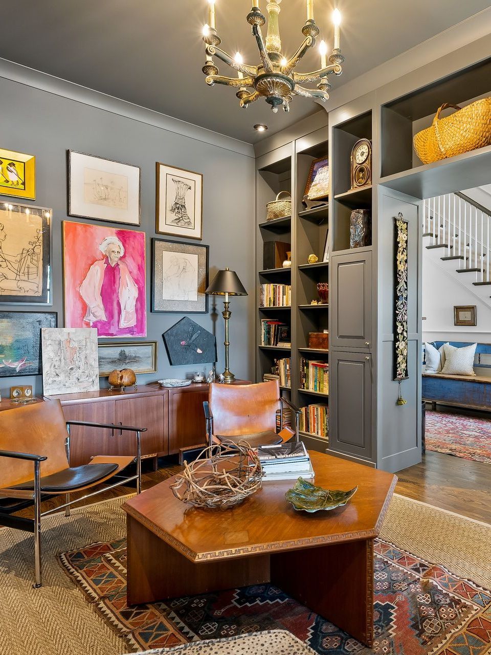 A living room with a coffee table , chairs , and a chandelier.