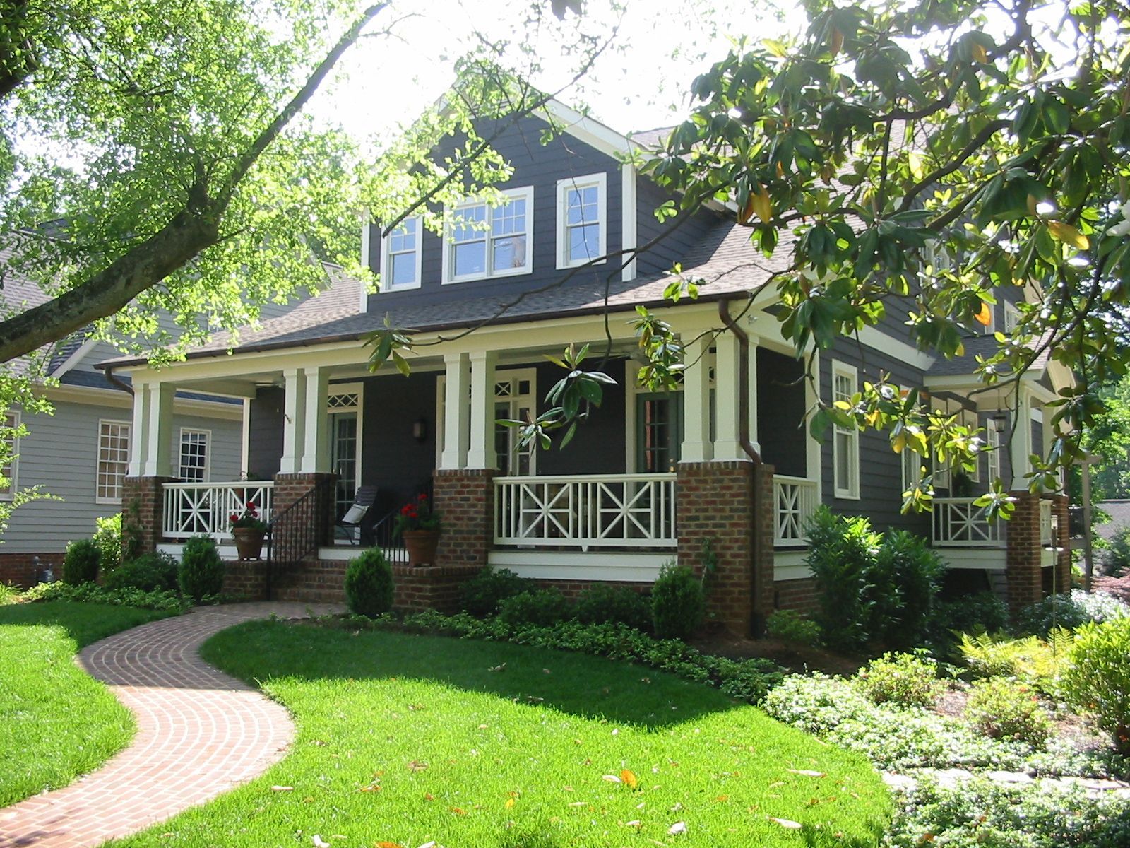 A house with a large porch and a brick walkway leading to it