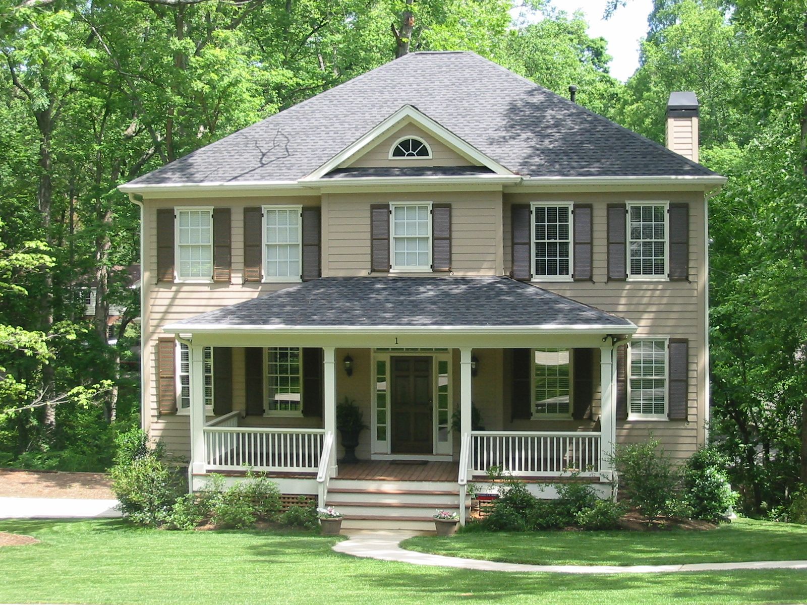 A house with a porch and shutters is surrounded by trees