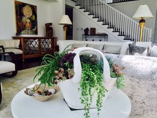 Living room with a round white coffee table, white sofa, and a staircase. A flower arrangement is on the table.