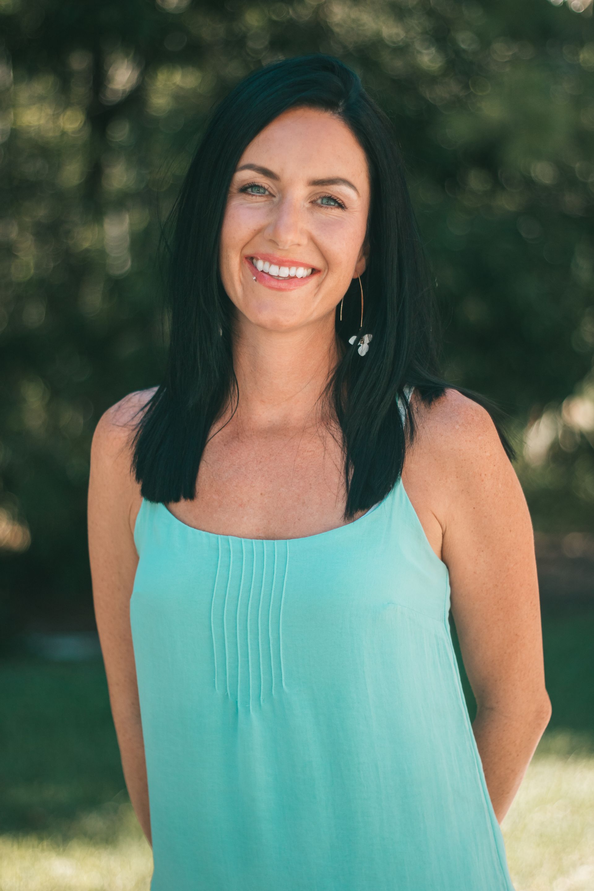 A woman in a blue tank top is smiling for the camera.