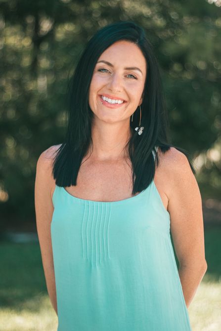 A woman in a blue tank top is smiling for the camera.