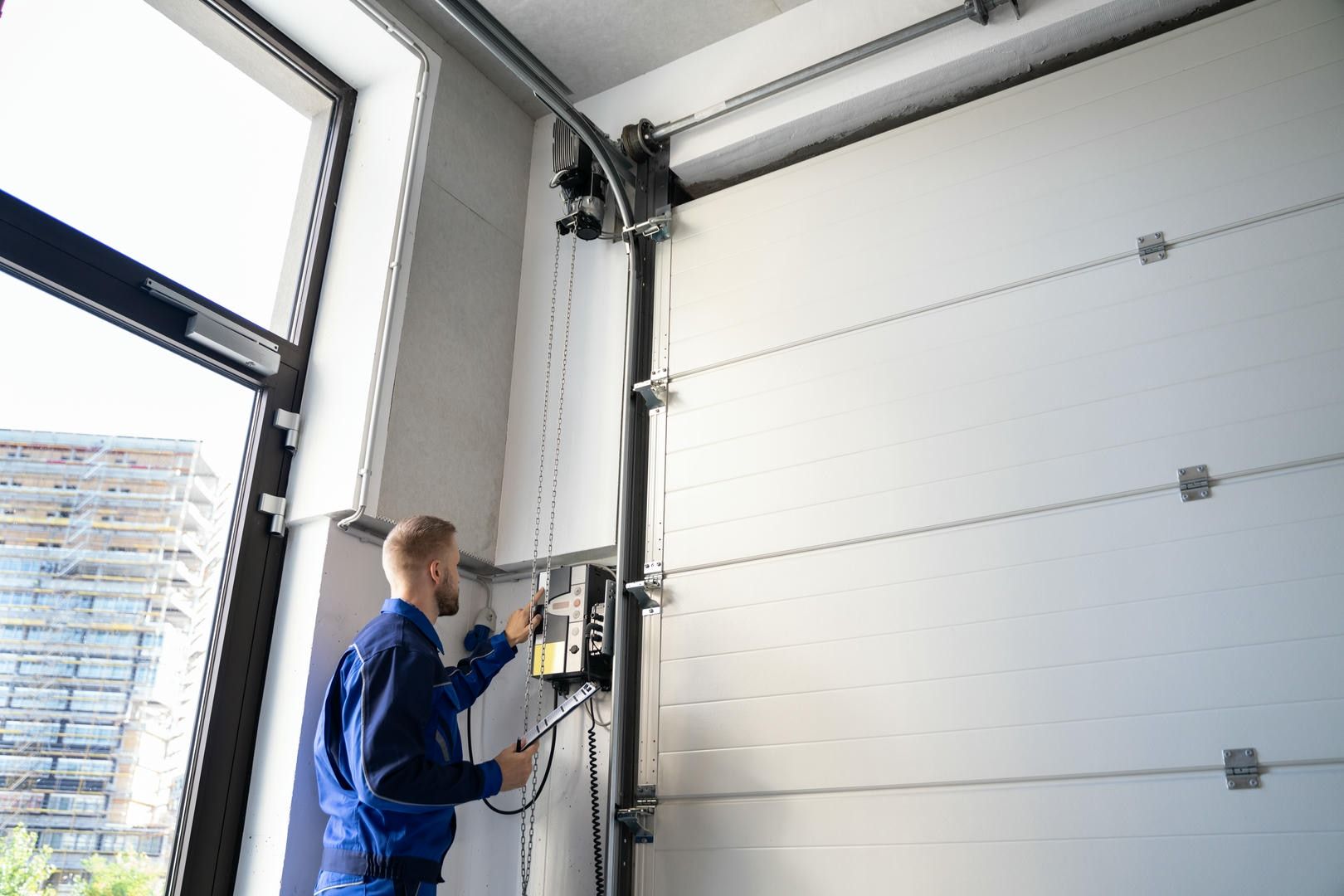 A man is working on a garage door in a garage.