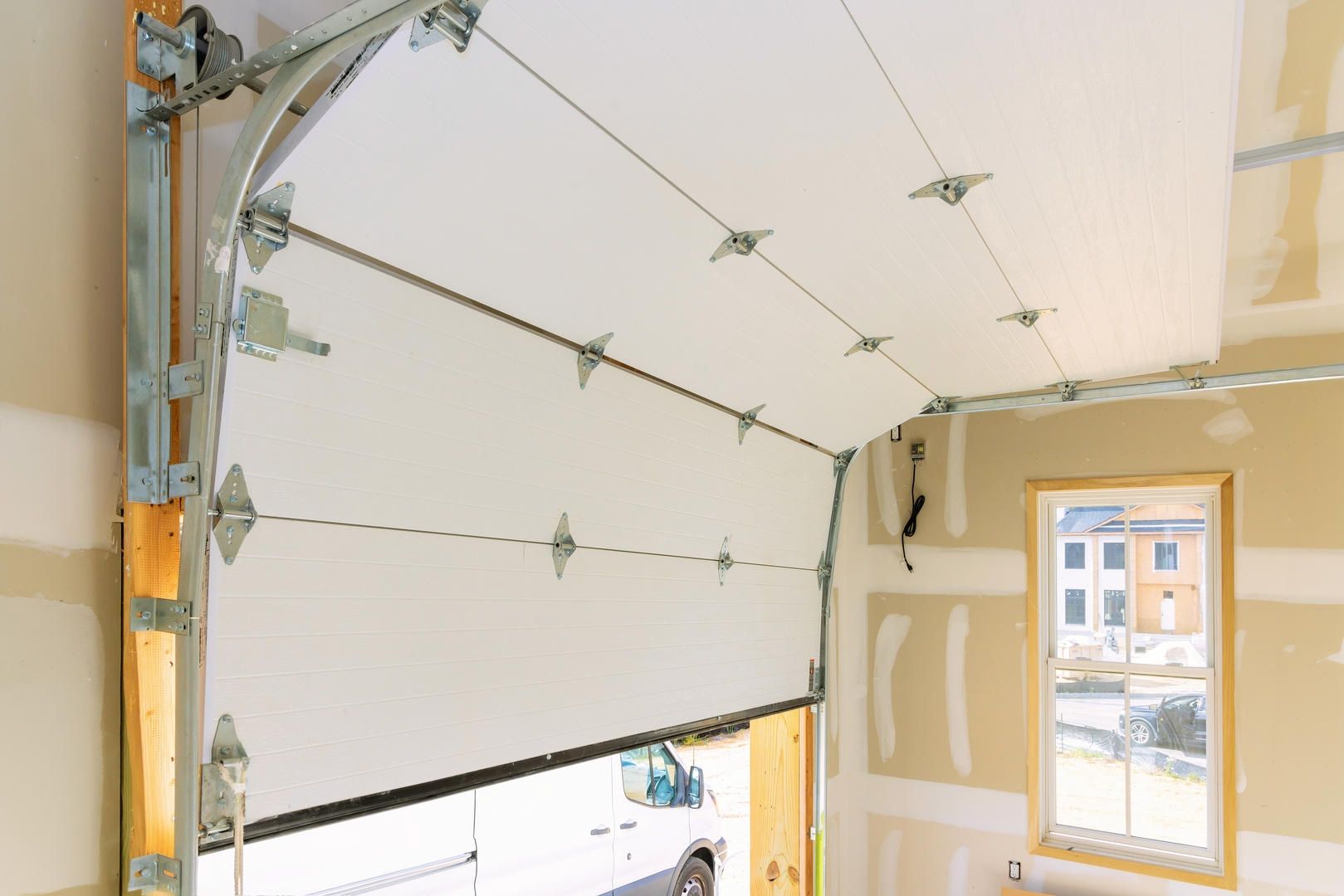 A garage door is open in a room with a window.
