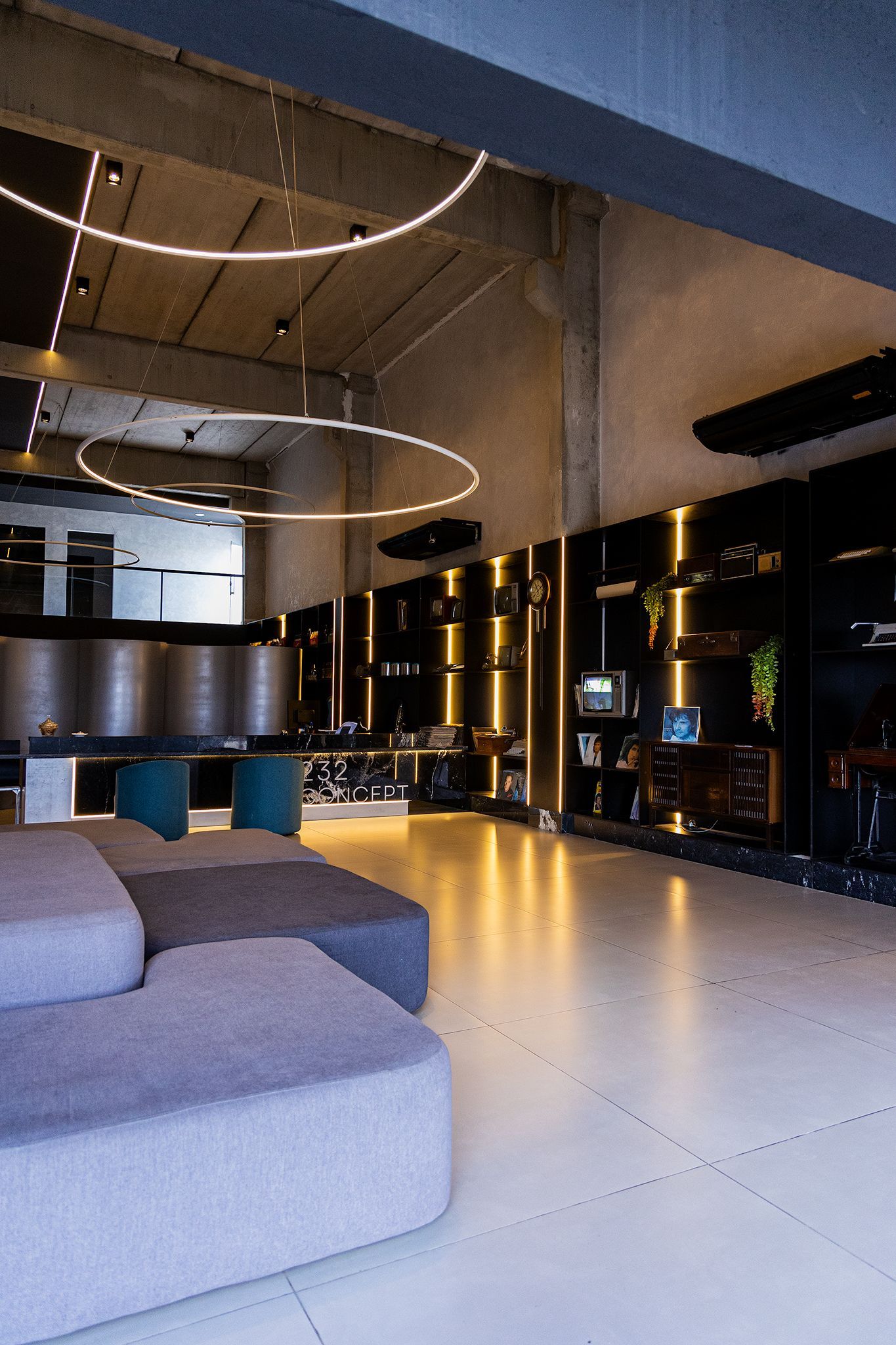 Interior moderno com sofás, prateleiras e luminárias circulares.