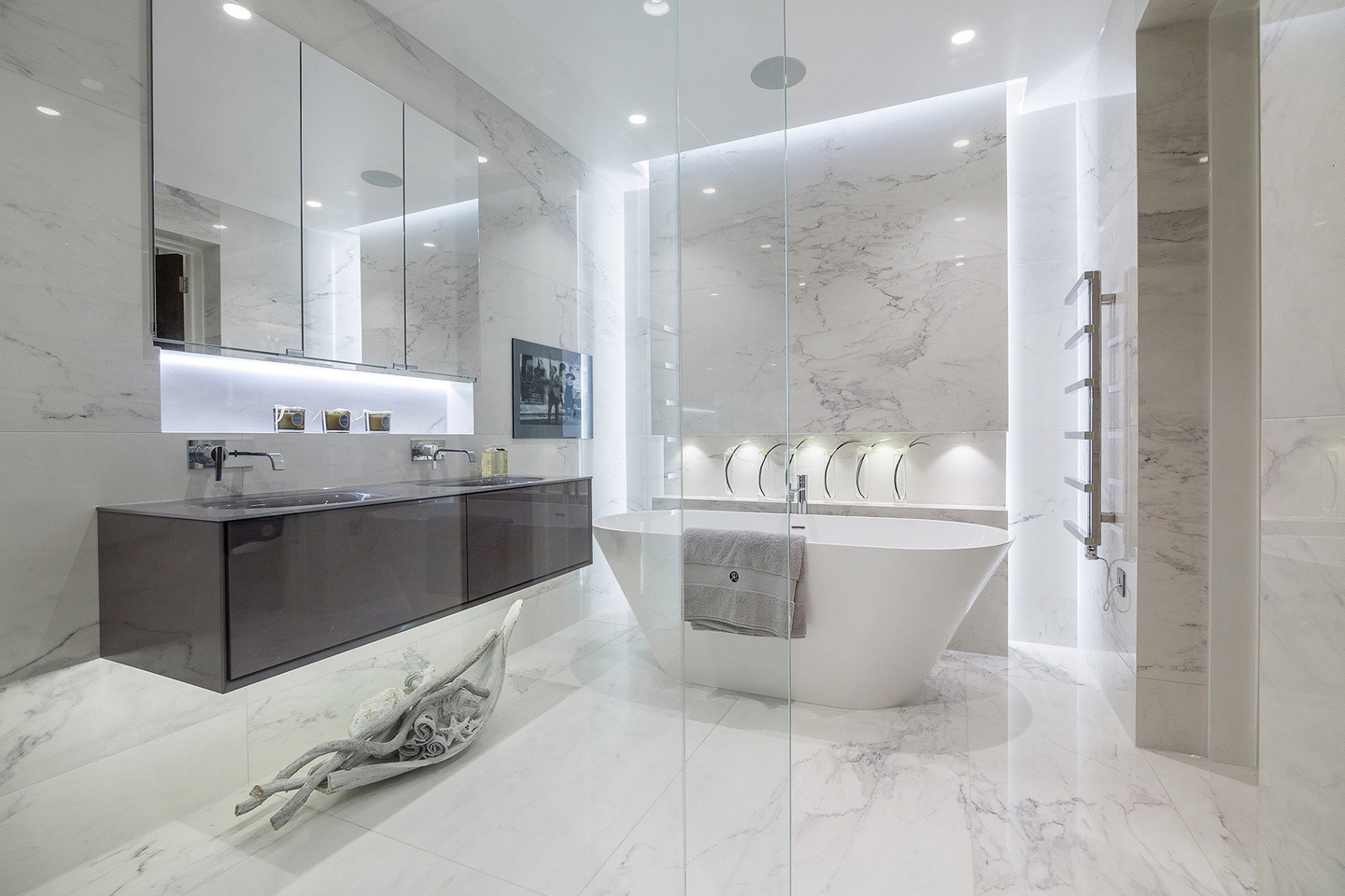 Modern white marble bathroom with a floating vanity, bathtub, and glass shower.