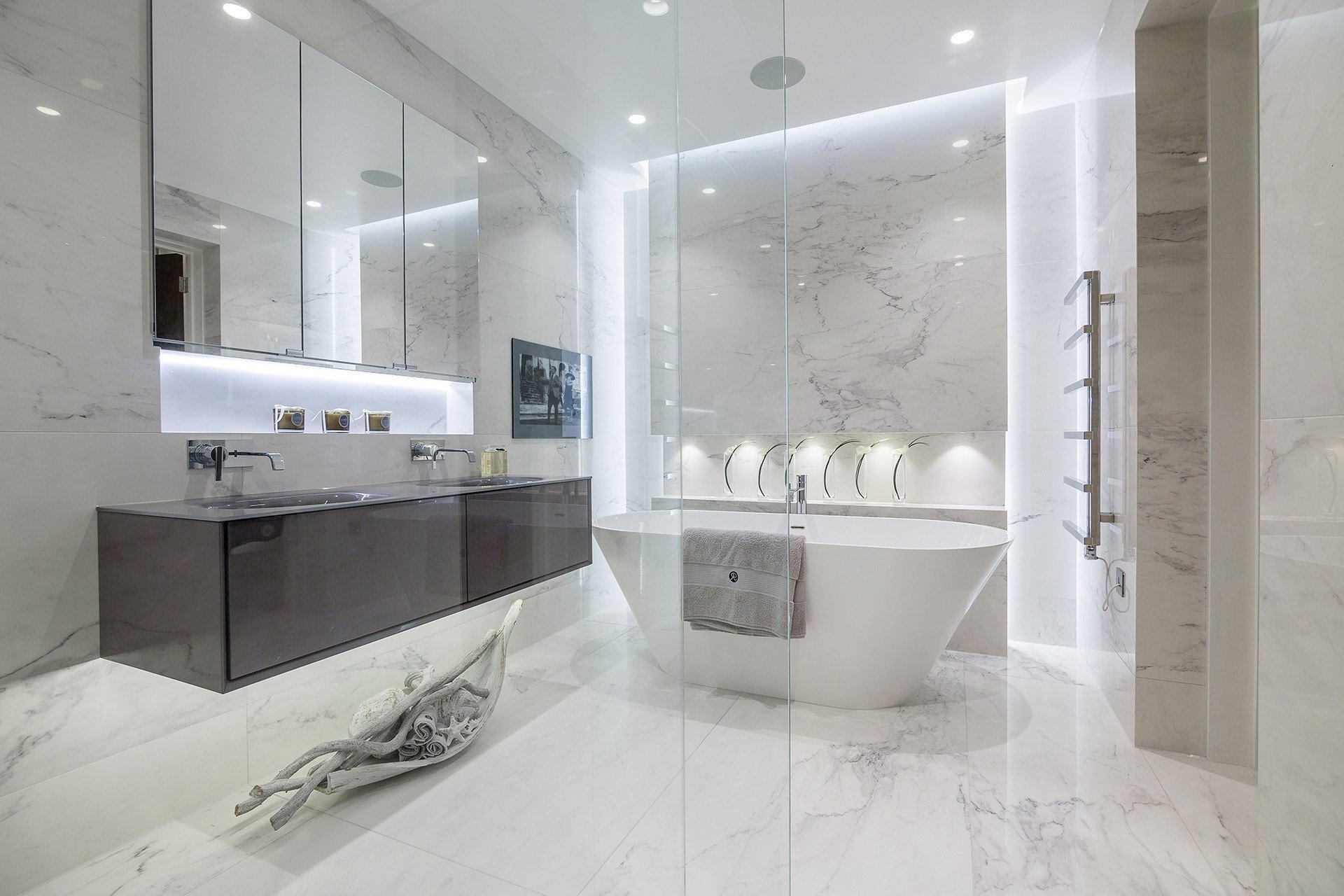 Modern, white marble bathroom tiling with a freestanding tub, glass shower, and floating vanity.