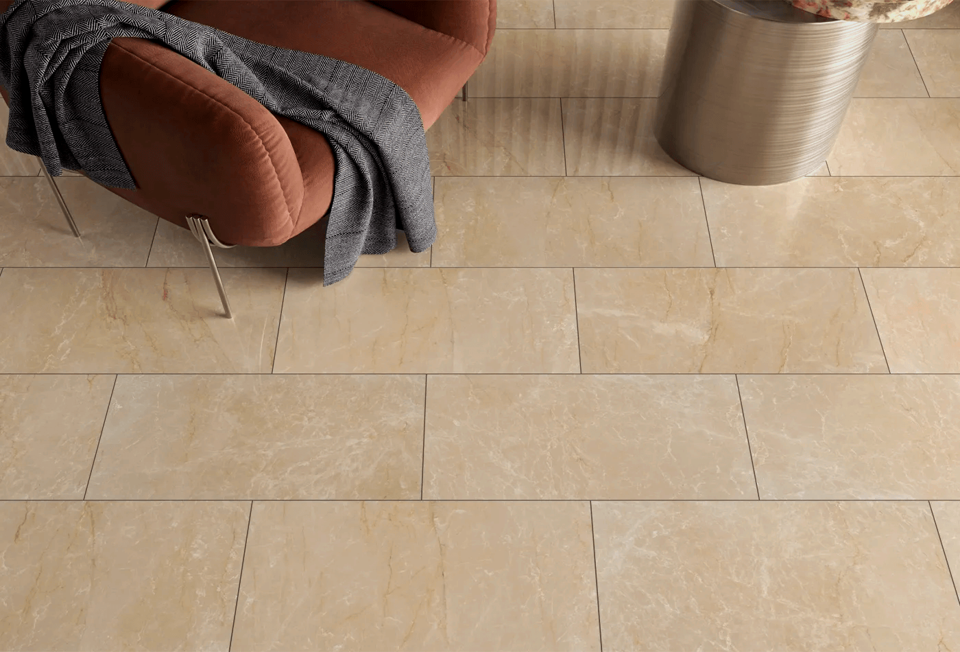 Beige floor tiling with a chair, throw, and silver side table.
