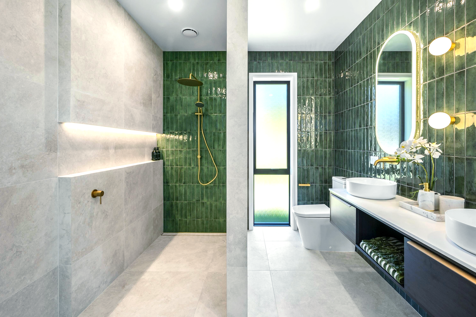 A bathroom with green tiles and a walk in shower.