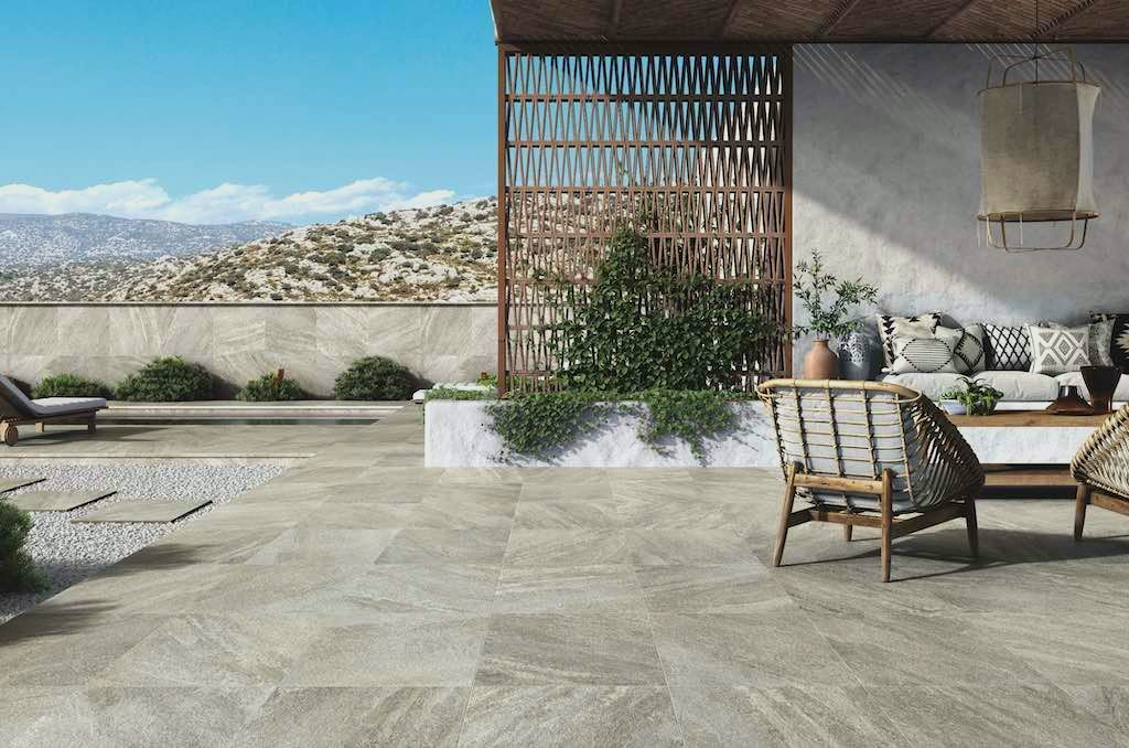 Patio with outdoor tiling in stone, wicker furniture, overlooking a mountain vista.