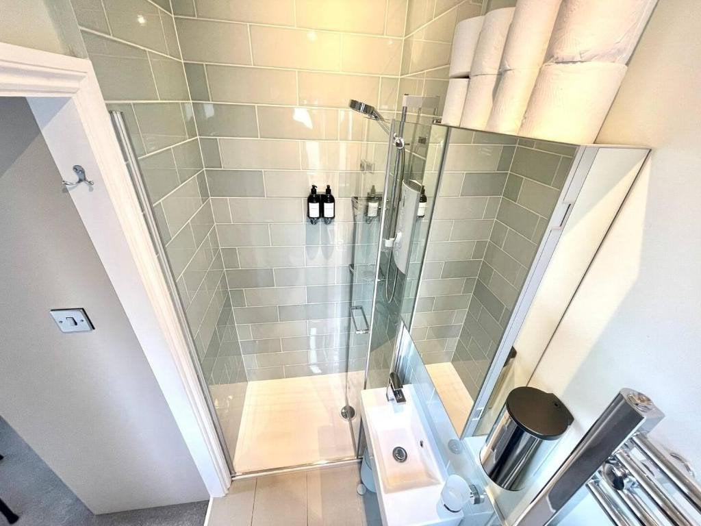 Modern shower tiling with glass doors, tiled walls, and chrome fixtures.