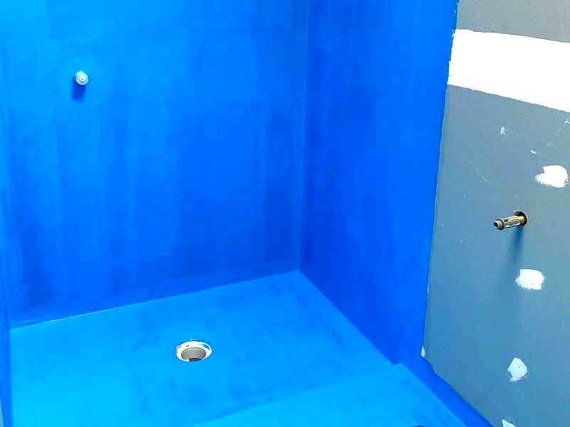 Blue waterproofed shower stall, showing drain and pipe fixtures, prepared for waterproofing services.