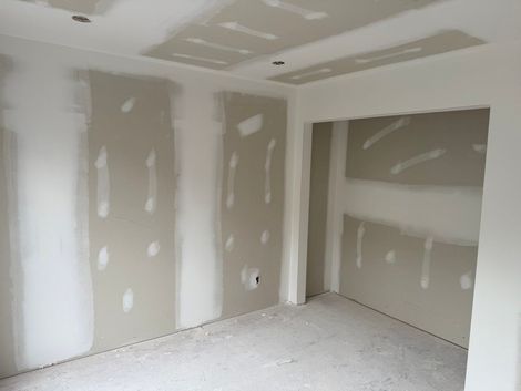 Intérieur en rénovation avec murs en gypse préparés et plafond suspendu partiellement installé.