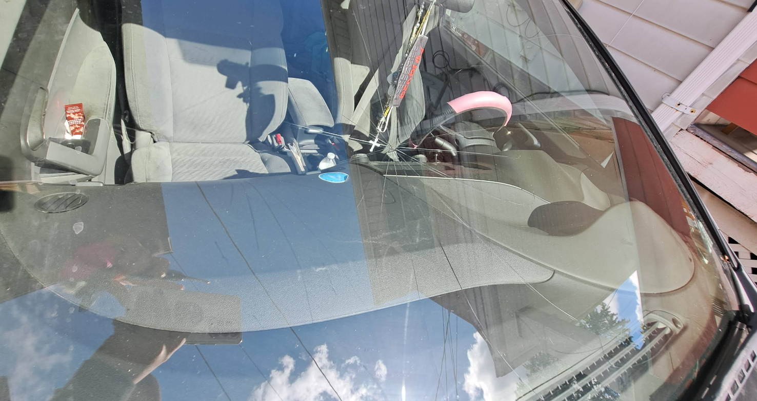 View from inside a car through windshield; seats visible, sunlight reflection.