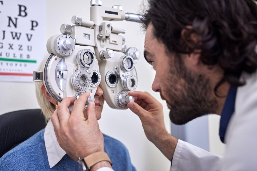 Eye doctor adjusting a phoropter for a patient during an eye exam