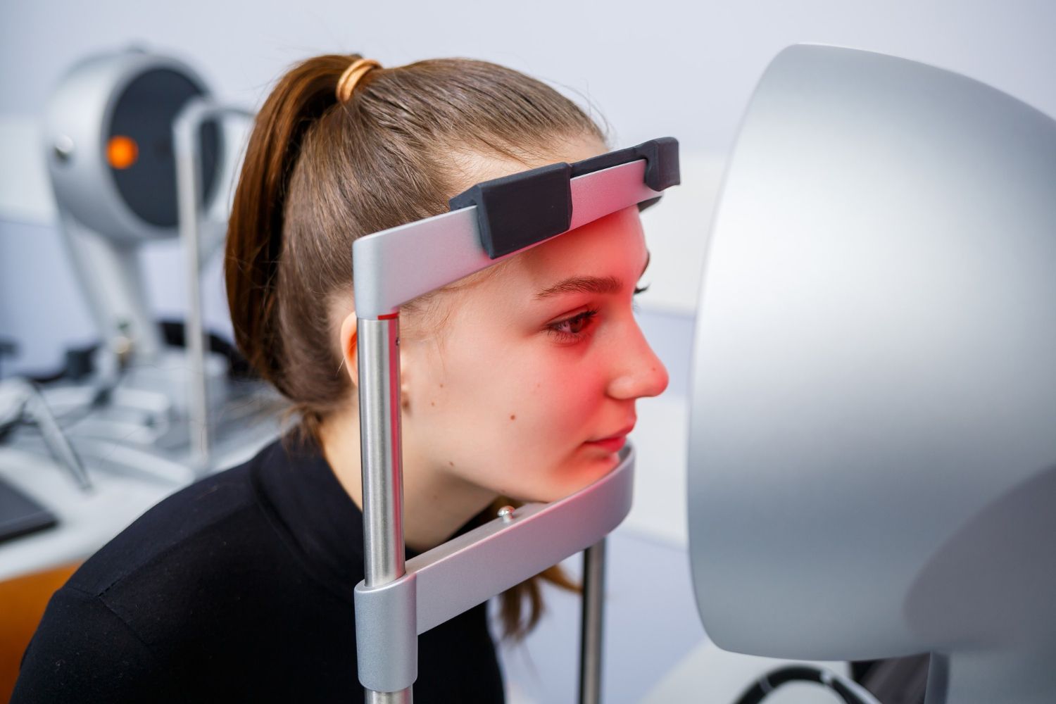 Person seated in a facial scanning device facing a large monitor in a lab setting