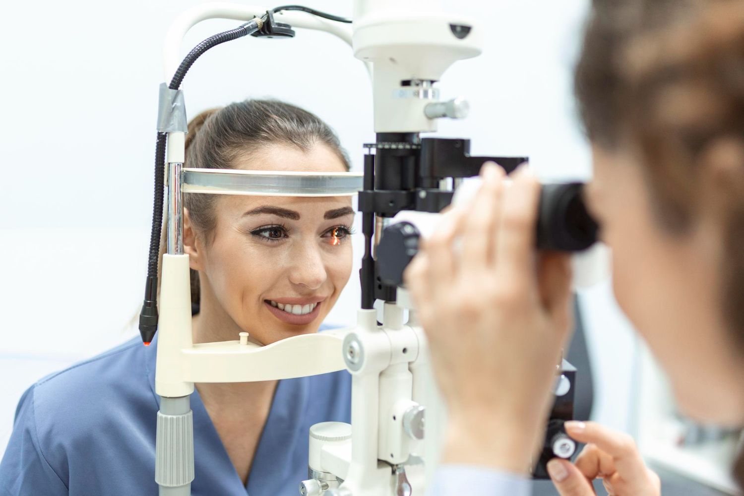 Patient undergoing an eye exam with a slit lamp while an optometrist examines her eyes