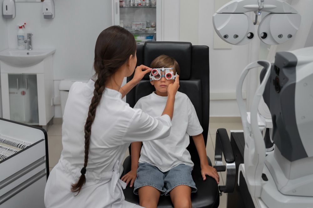 Eye exam in a clinic as an optometrist adjusts glasses on a child seated in an exam chair