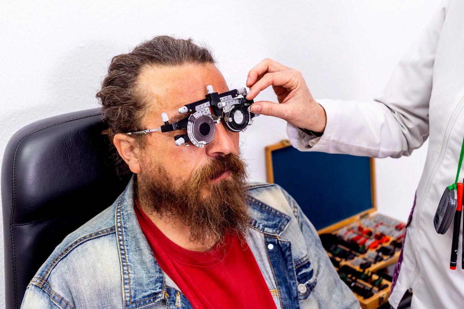 Man with beard getting an eye exam while wearing trial frames in a clinic