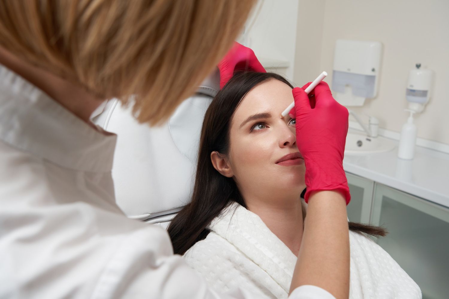 Patient undergoing an eye exam with a slit lamp while an optometrist examines her eyes