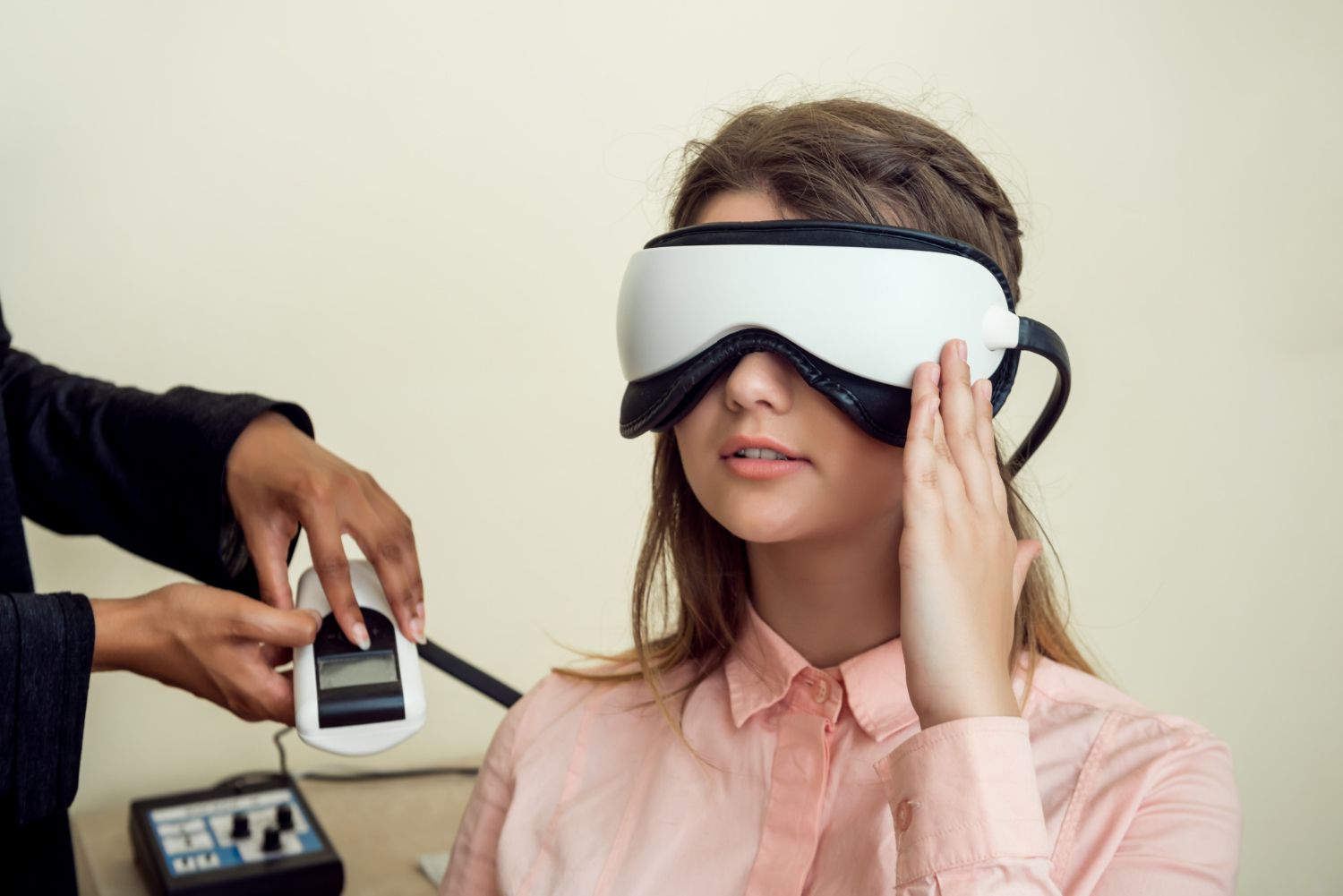 Woman wearing a white VR headset while another person adjusts it with a handheld device