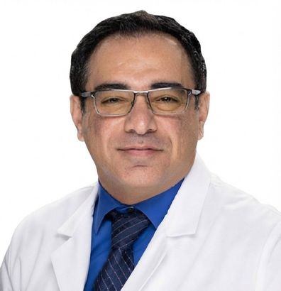 Portrait of a smiling doctor in a white coat, blue shirt, and glasses on a white background