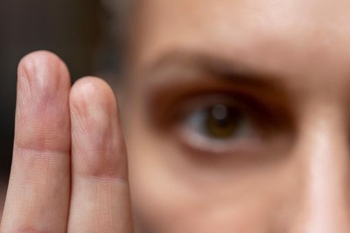 Close-up of a face with a hand raised near the eye, as if peeking through fingers to represent EMDR therapy in San Antonio