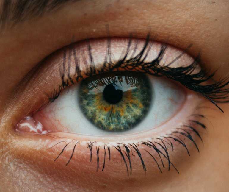 Close-up of a green-blue eye with long eyelashes and natural makeup