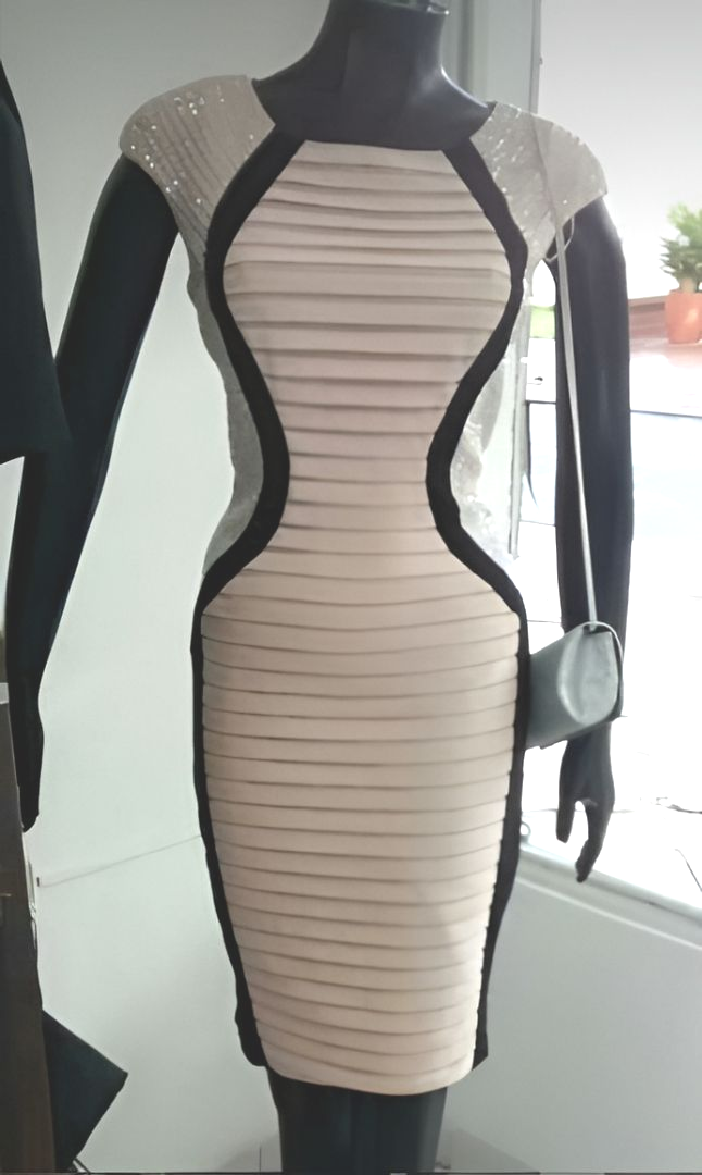 Maniquí con un vestido ajustado de rayas beige y negras con mangas transparentes y detalles en los hombros.