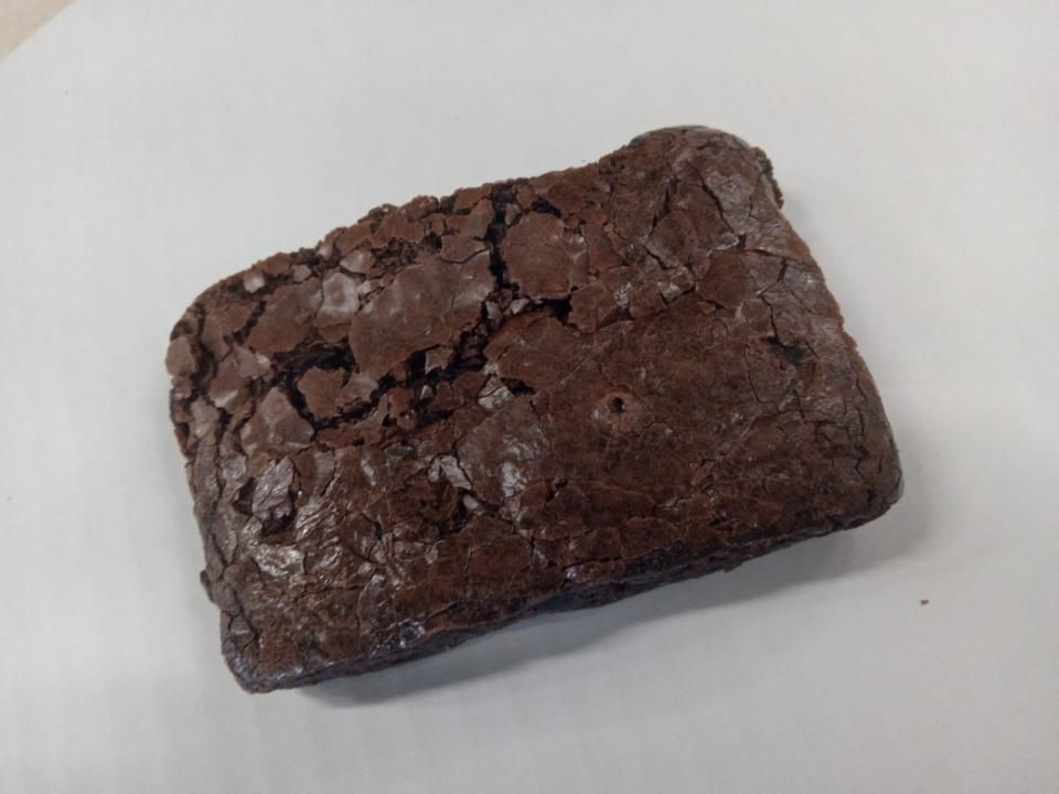 Chocolate brownie on a white plate, with a cracked, shiny top.