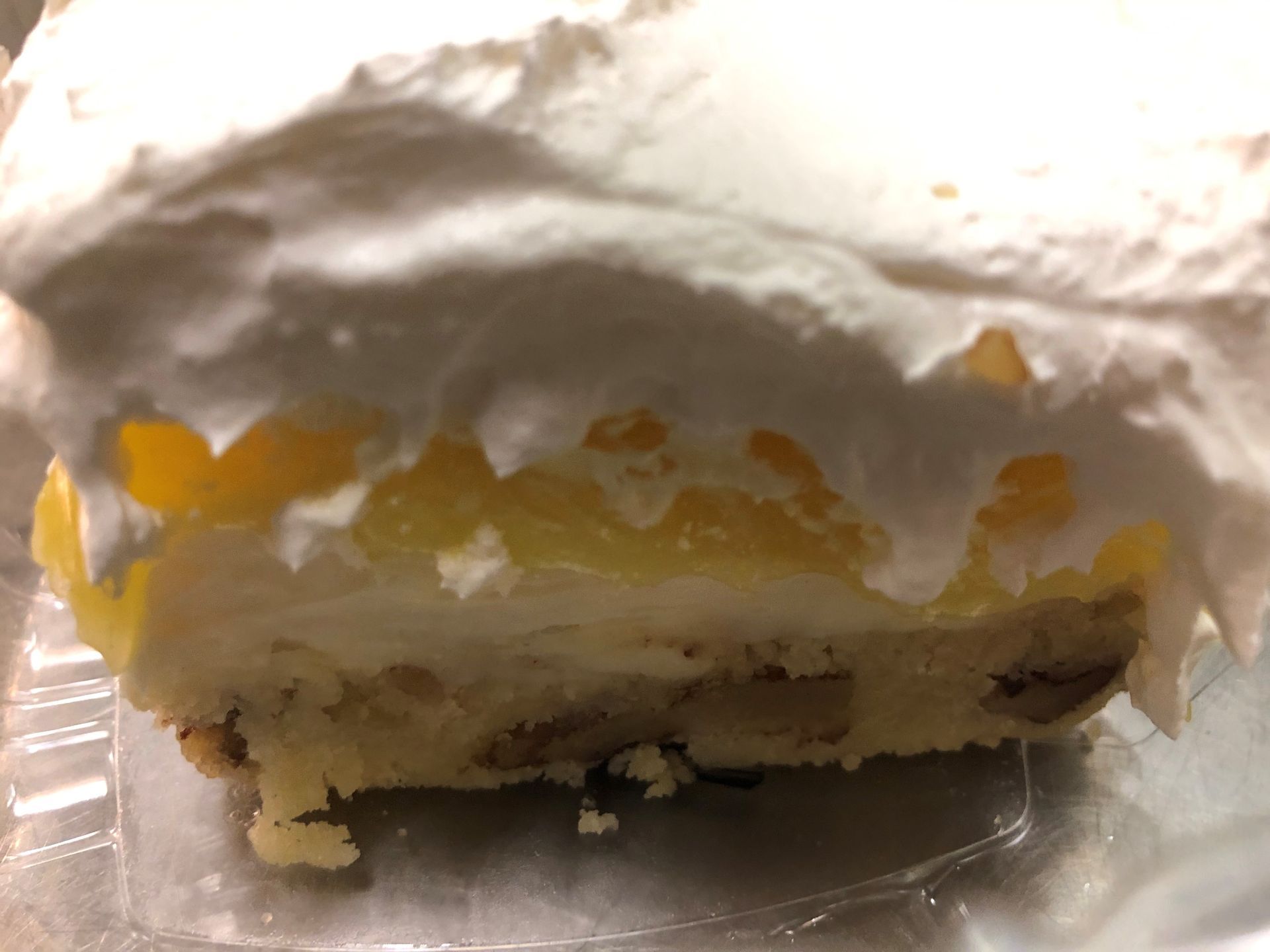 Slice of layered dessert: pecan crust, cream cheese filling, pineapple, whipped cream.