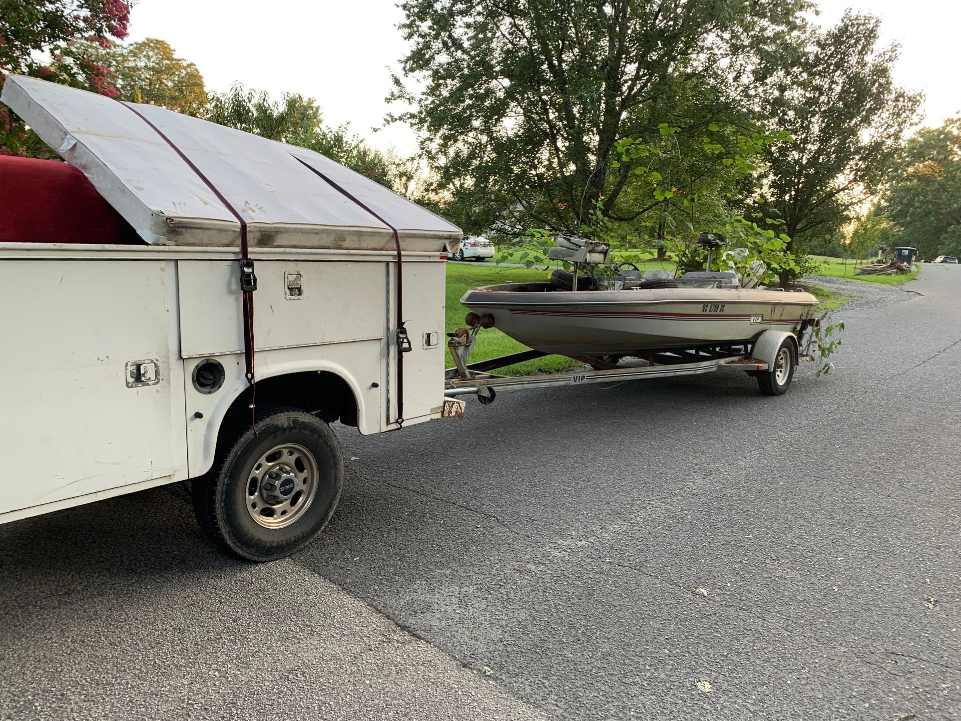 A white truck is towing a boat on a trailer.
