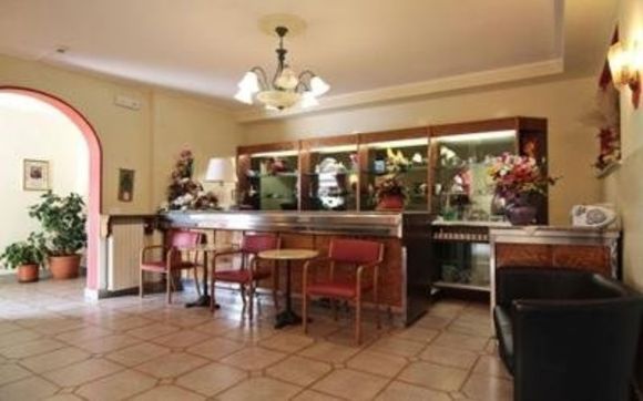 Sala da pranzo con pavimento piastrellato, bancone in legno, sedie e credenze, illuminata da calde luci a soffitto.