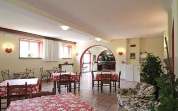 Sala da pranzo luminosa con tovaglie rosse, porta ad arco e divano a fiori vicino alla finestra