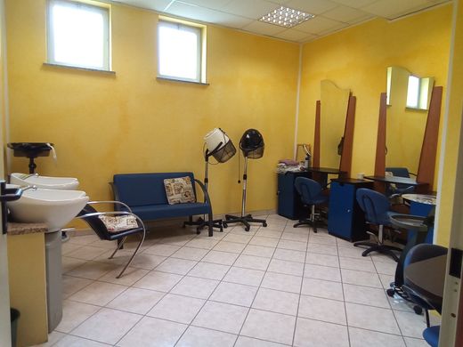 Interno di un salone di parrucchiere con pareti gialle, poltrone da acconciatura, specchi, lavatesta e attrezzature da salone.