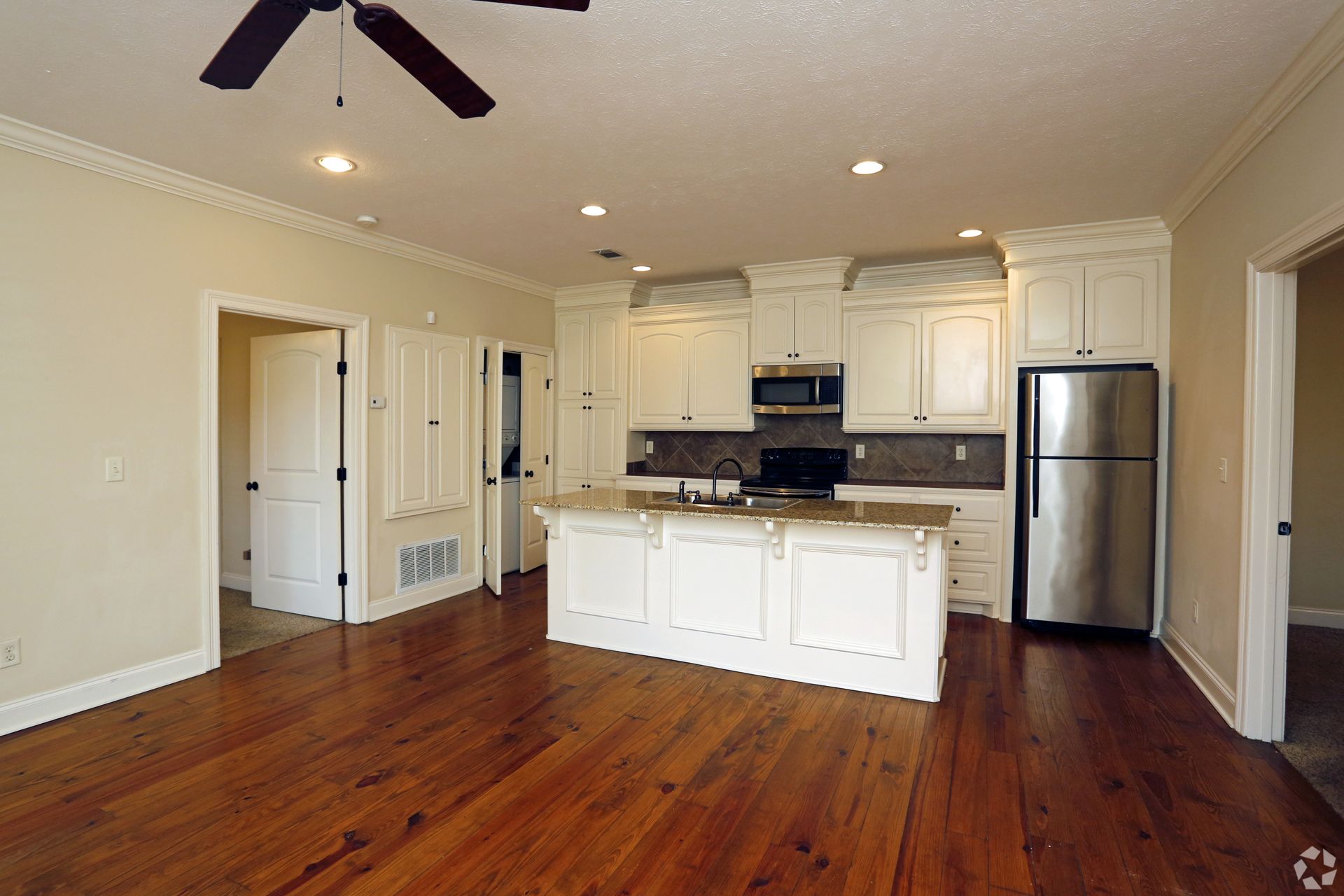A kitchen with white cabinets and a stainless steel refrigerator