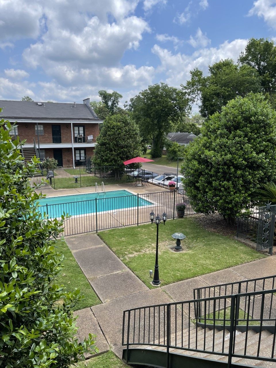 A large swimming pool is surrounded by trees and a building