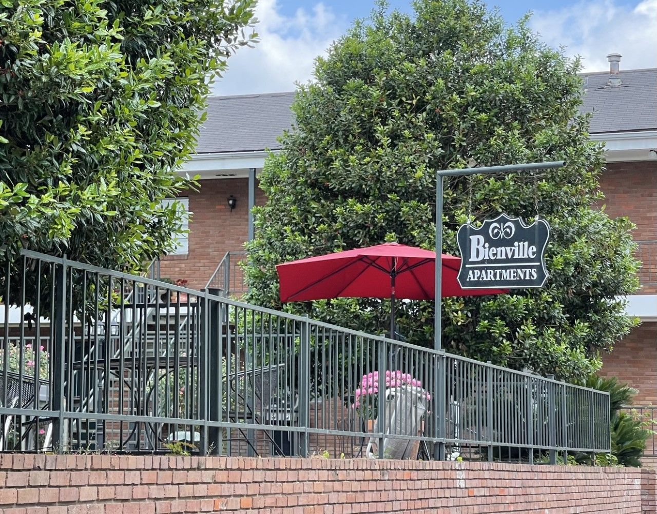 A brick fence with a red umbrella and a sign that says beauville apartments