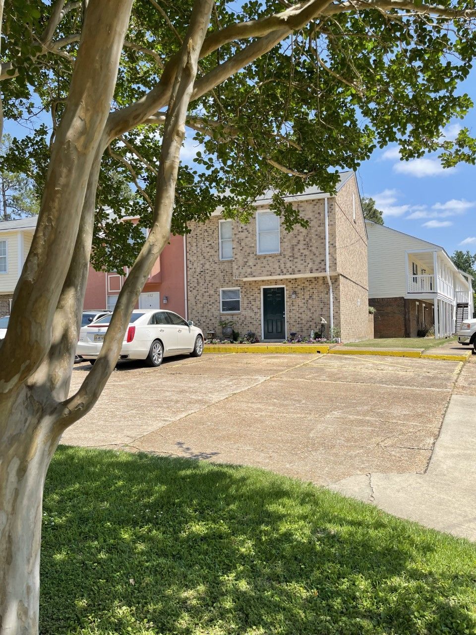 A white car is parked in front of a brick apartment building.