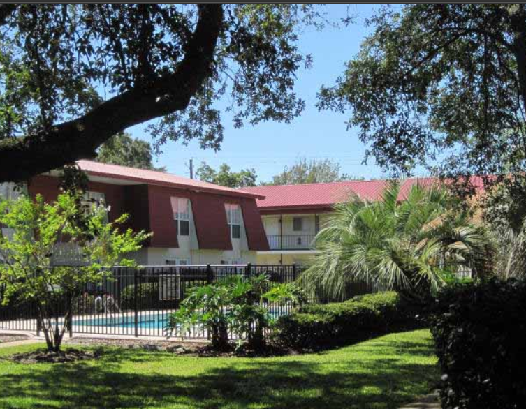 A building with a red roof and a pool in front of it