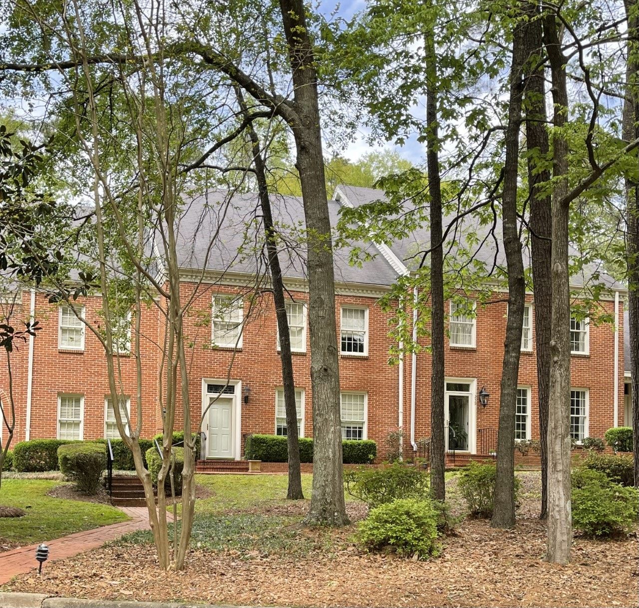 A large red brick house with trees in front of it
