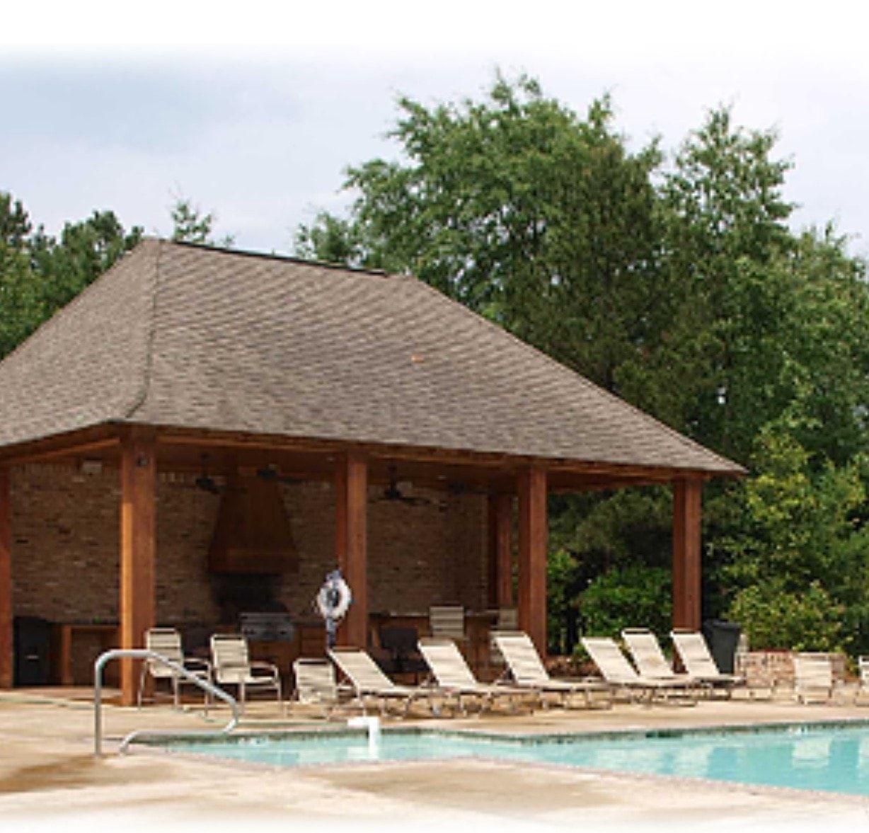 A pool with a pavilion and chairs around it