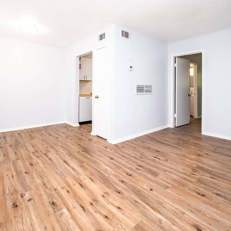 An empty room with hardwood floors and white walls.