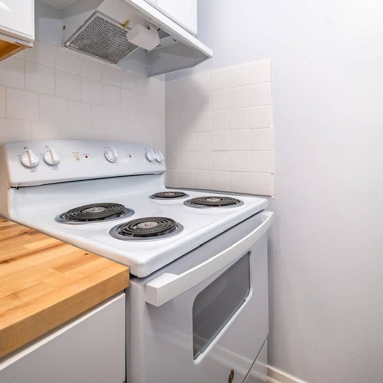 A white stove and oven in a kitchen with a wooden counter top