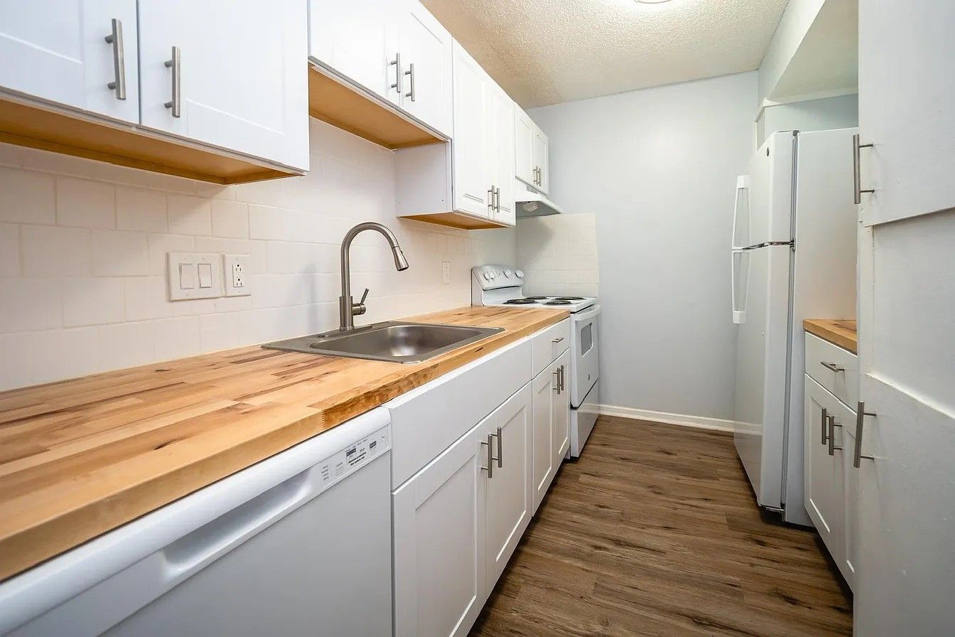 A kitchen with white cabinets and wooden counter tops