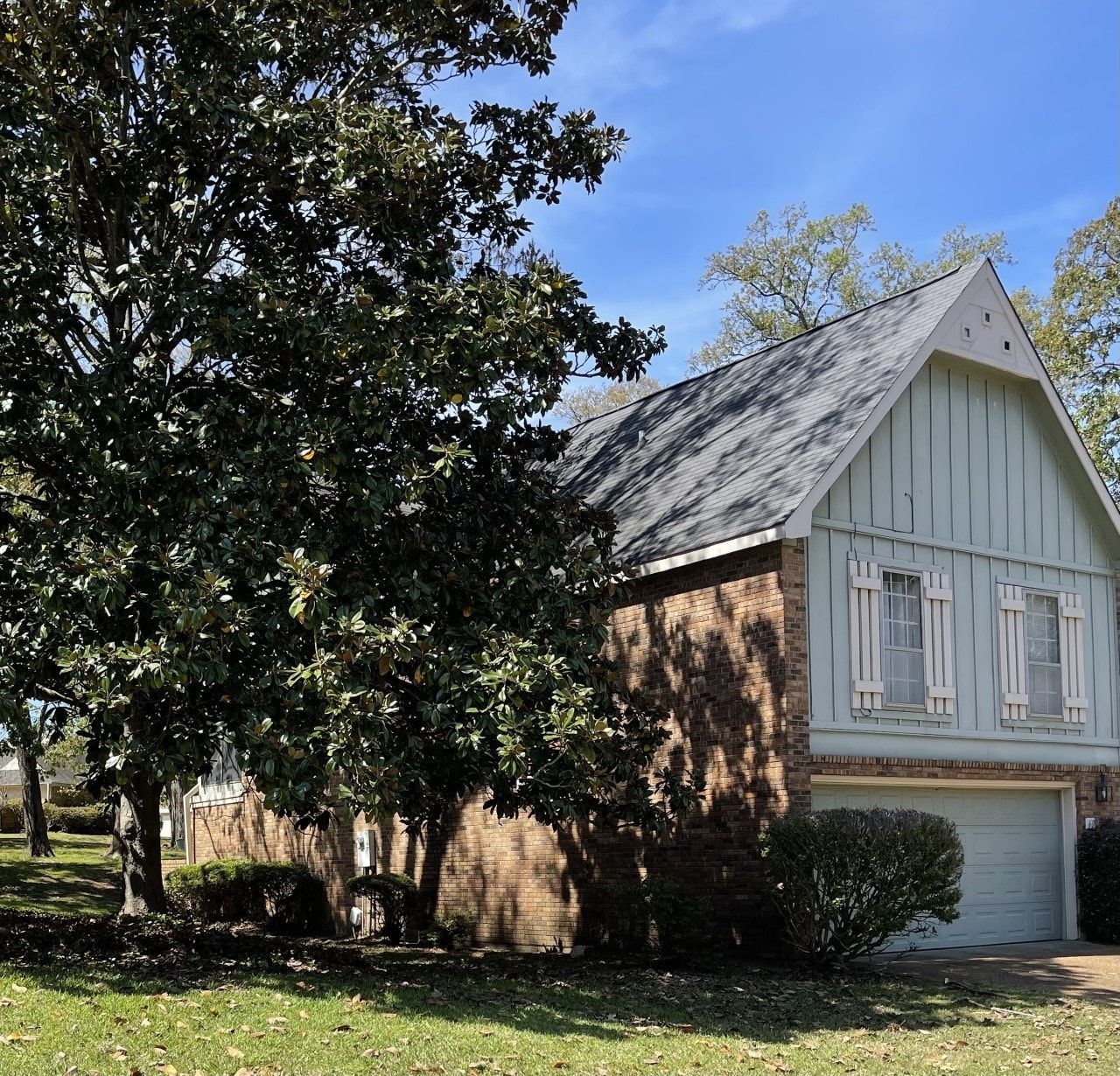 A house with a white roof and a tree in front of it