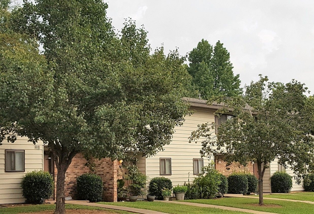 A row of apartment buildings with trees in front of them.