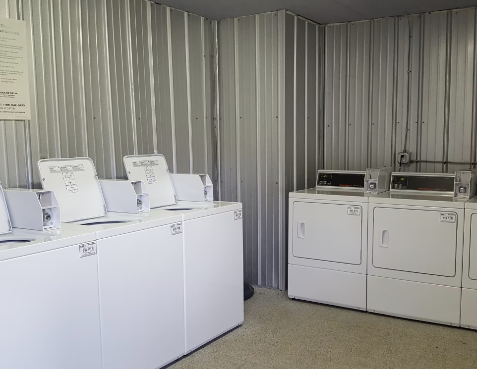 A row of white washers and dryers in a laundromat.
